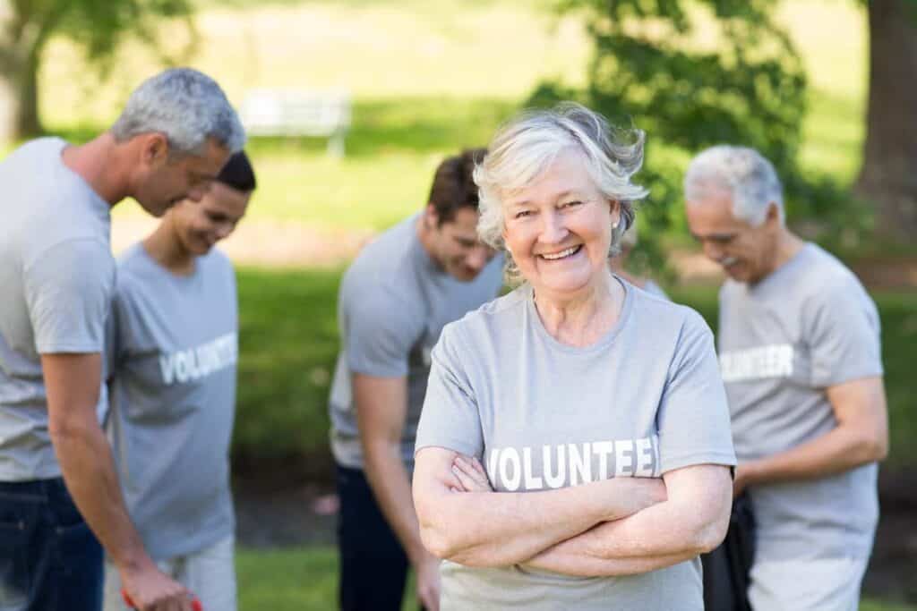 Senior woman smiling with fellow volunteers in a park.
